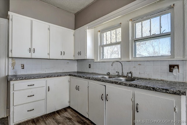 kitchen with decorative backsplash, white cabinets, sink, dark hardwood / wood-style flooring, and a textured ceiling