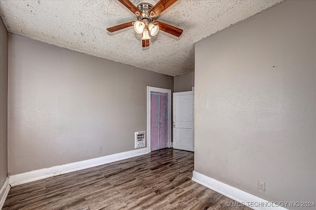 empty room featuring heating unit, dark hardwood / wood-style flooring, a textured ceiling, and ceiling fan