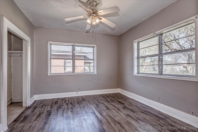 unfurnished bedroom featuring ceiling fan, a closet, dark hardwood / wood-style floors, and multiple windows