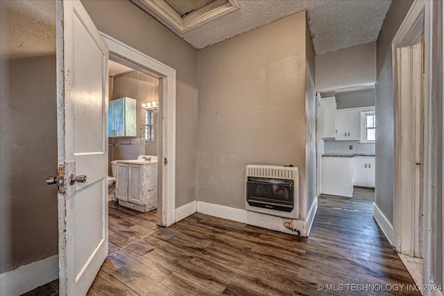 corridor featuring a textured ceiling, dark wood-type flooring, and heating unit