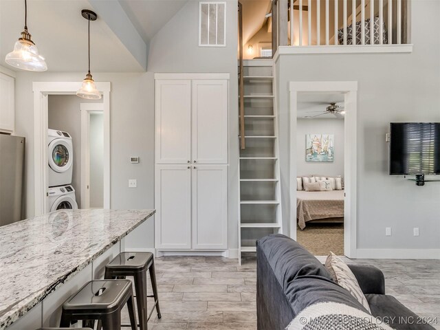 86 Ridgeline, Carlton Landing, OK 74432 - kitchen featuring visible vents, freestanding refrigerator, stacked washing maching and dryer, light stone countertops, and pendant lighting