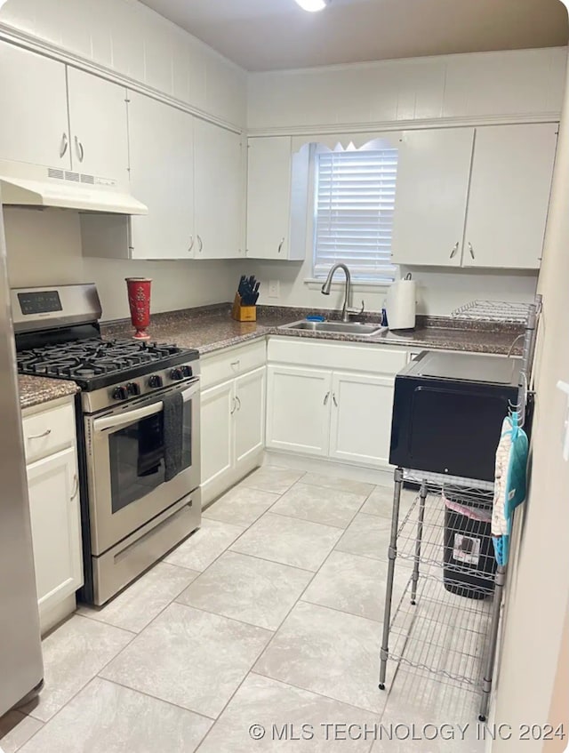 kitchen with light tile patterned flooring, stainless steel gas range oven, sink, and white cabinetry