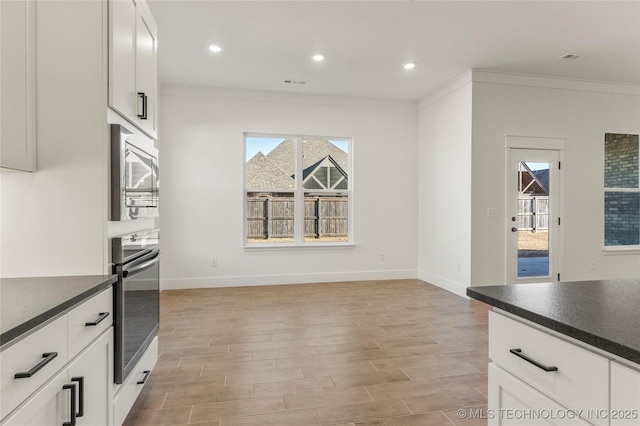 2804 E Northampton St, Broken Arrow, OK 74014 - kitchen featuring stainless steel appliances, dark countertops, light wood-style floors, white cabinets, and ornamental molding
