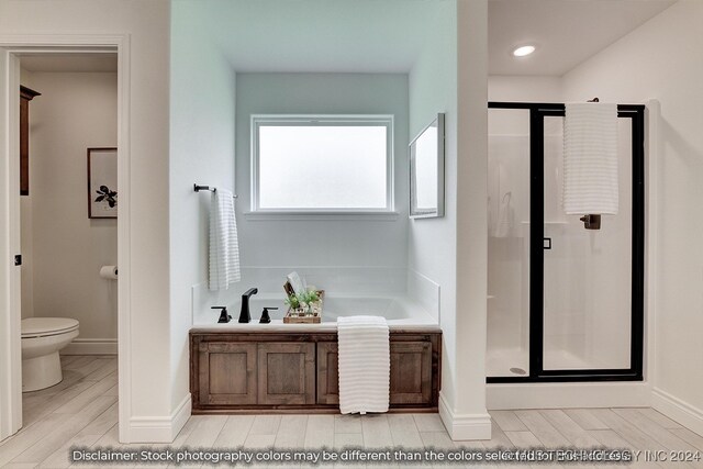 bathroom with hardwood / wood-style flooring, toilet, and separate shower and tub