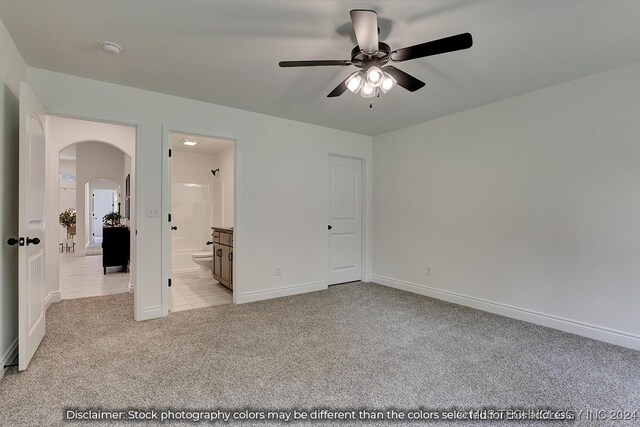 unfurnished bedroom with ceiling fan, light colored carpet, and ensuite bath