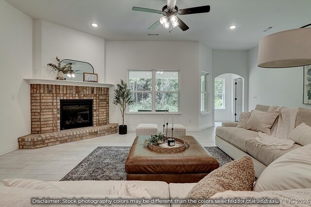 living room with a brick fireplace, light hardwood / wood-style floors, and ceiling fan