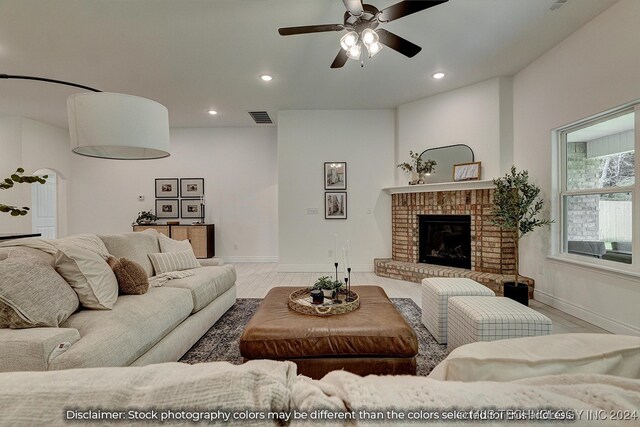 living room with a brick fireplace, light hardwood / wood-style floors, and ceiling fan