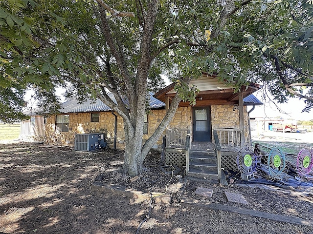 exterior space featuring cooling unit, a porch, and stone siding