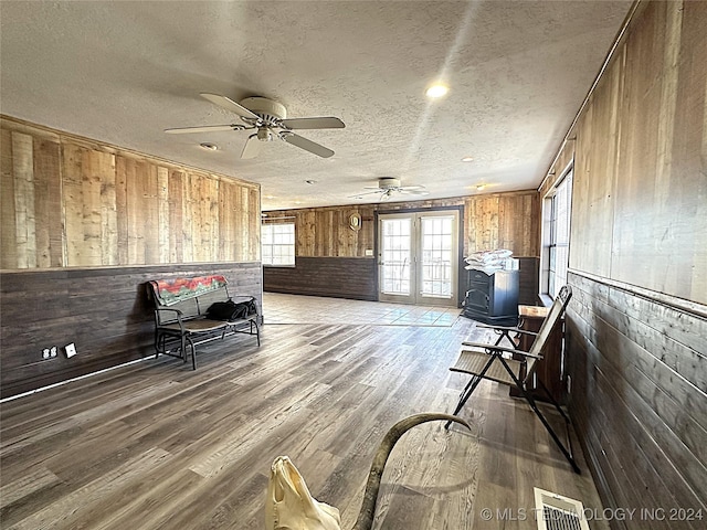 sitting room featuring wood walls, ceiling fan, light wood finished floors, visible vents, and a textured ceiling