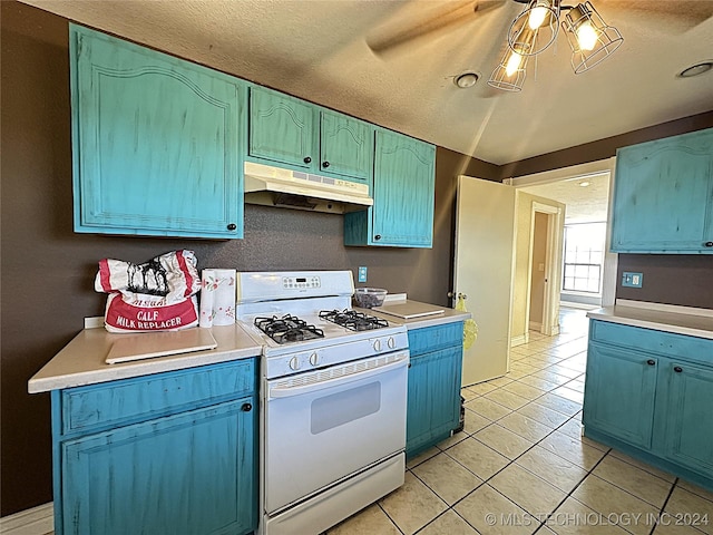 kitchen with light countertops, light tile patterned flooring, white gas stove, and under cabinet range hood