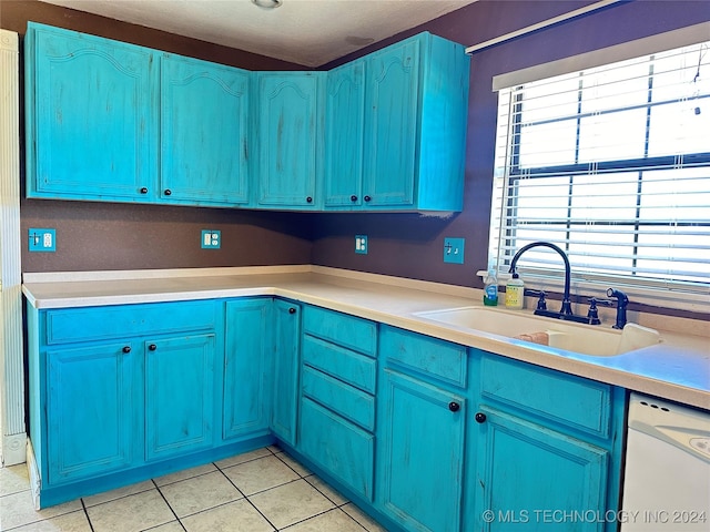 kitchen featuring light tile patterned floors, a sink, white dishwasher, and blue cabinets