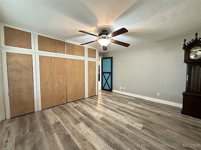 unfurnished bedroom with a textured ceiling, ceiling fan, and hardwood / wood-style flooring