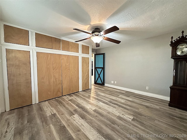 unfurnished bedroom featuring a textured ceiling, wood finished floors, ceiling fan, and baseboards