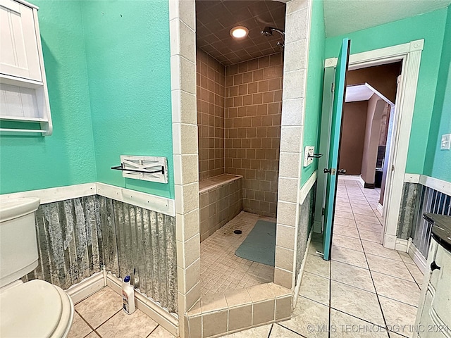 full bath featuring toilet, tile patterned flooring, a shower stall, and wainscoting
