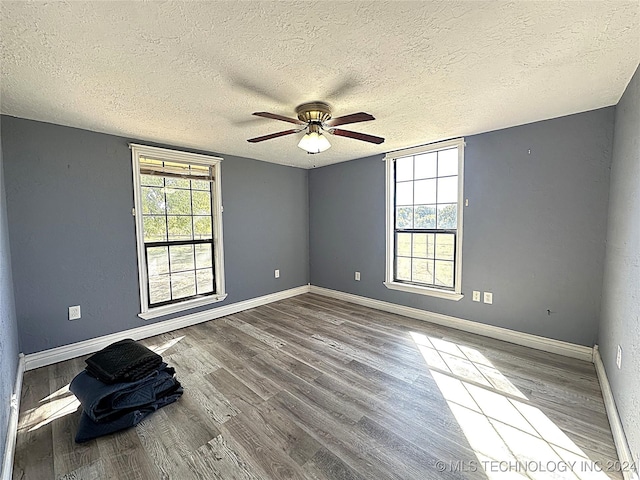 unfurnished room with a textured ceiling, wood finished floors, a ceiling fan, and baseboards