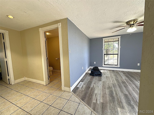 spare room featuring a ceiling fan, a textured ceiling, and a textured wall