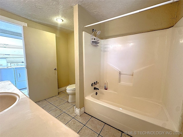 bathroom with washtub / shower combination, a textured ceiling, washing machine and clothes dryer, toilet, and tile patterned floors