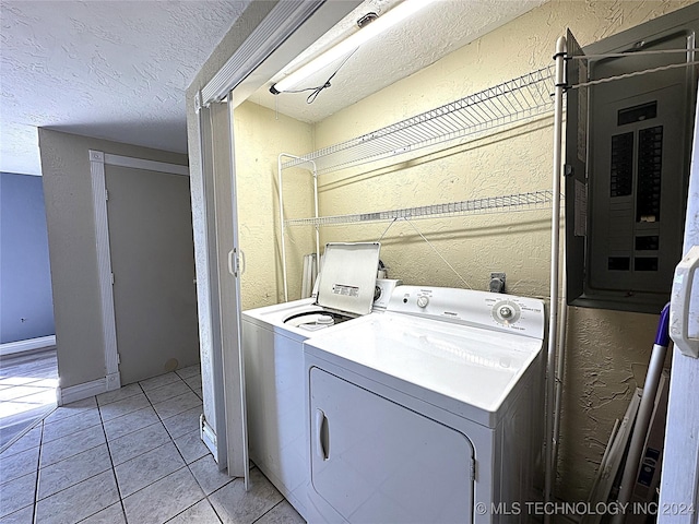 washroom featuring laundry area, light tile patterned floors, a textured wall, washing machine and dryer, and a textured ceiling