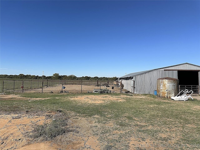view of yard with fence, an outdoor structure, a rural view, and an outbuilding