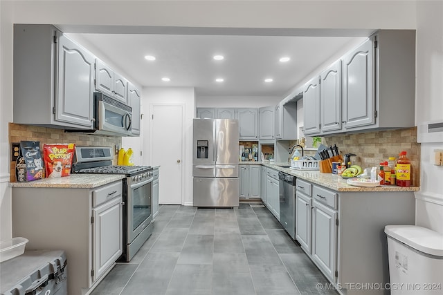 kitchen with gray cabinets, stainless steel appliances, sink, and decorative backsplash