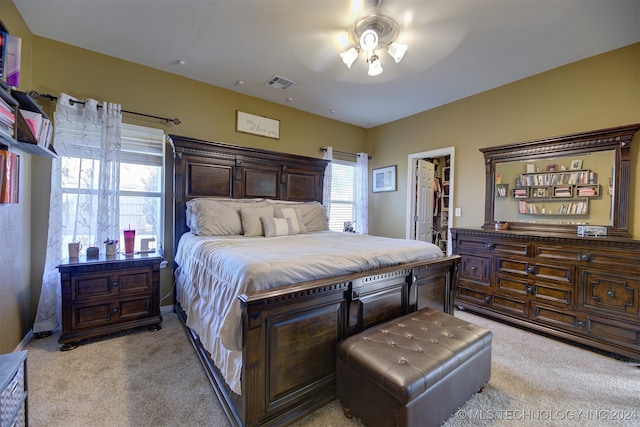 bedroom featuring a spacious closet, light carpet, ceiling fan, and a closet