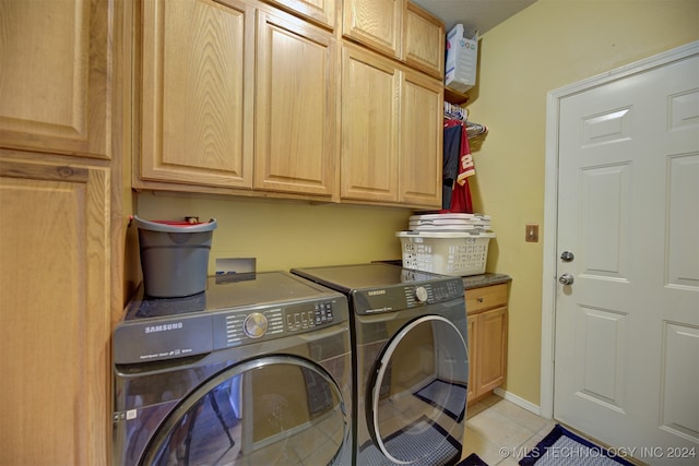 clothes washing area featuring light tile patterned flooring, cabinets, and washing machine and clothes dryer