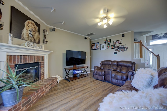 living room featuring a fireplace, hardwood / wood-style flooring, ceiling fan, and crown molding