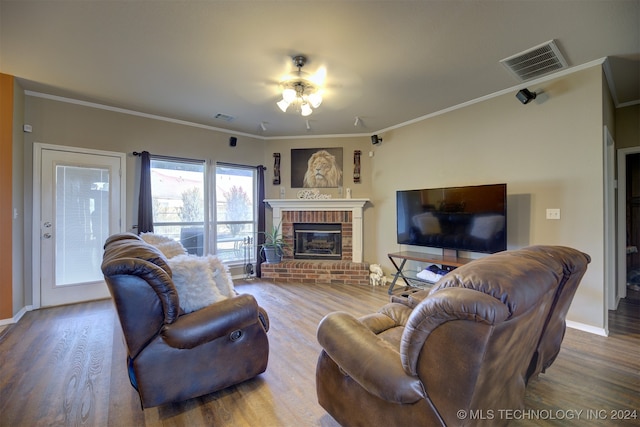 living room with a brick fireplace, hardwood / wood-style floors, ceiling fan, and crown molding