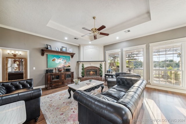 living area with visible vents, ornamental molding, a tray ceiling, and wood finished floors