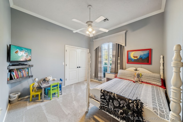 carpeted bedroom with visible vents, a ceiling fan, a closet, crown molding, and baseboards