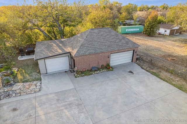 exterior space with brick siding, driveway, a shingled roof, and a garage