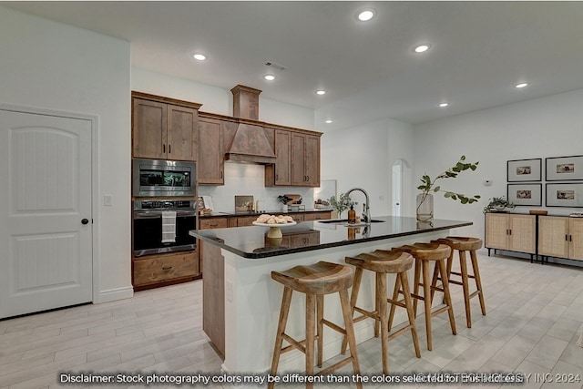 kitchen featuring light wood-type flooring, a kitchen island with sink, a breakfast bar, sink, and appliances with stainless steel finishes