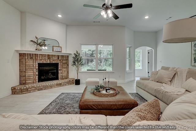 living room with a brick fireplace, ceiling fan, and light hardwood / wood-style floors