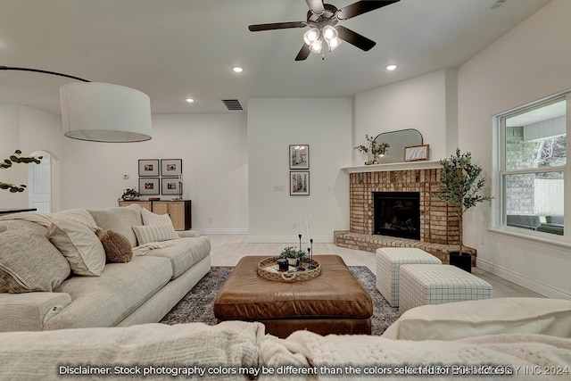 living room featuring a fireplace, light hardwood / wood-style floors, and ceiling fan