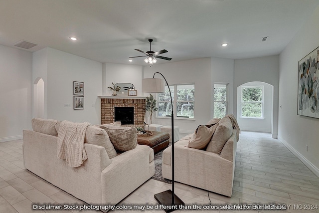 living room with a brick fireplace, light hardwood / wood-style floors, and ceiling fan