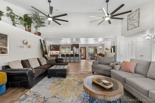 living room with hardwood / wood-style flooring, ceiling fan, and a towering ceiling