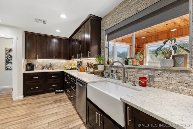 kitchen featuring light stone counters, sink, wooden walls, light hardwood / wood-style flooring, and decorative backsplash