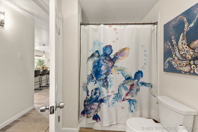 bathroom featuring wood-type flooring, a shower with shower curtain, a textured ceiling, and toilet