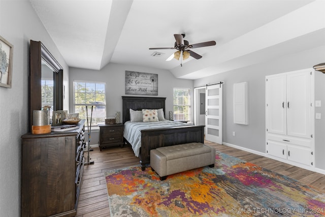 bedroom featuring dark wood-type flooring, ceiling fan, and a barn door