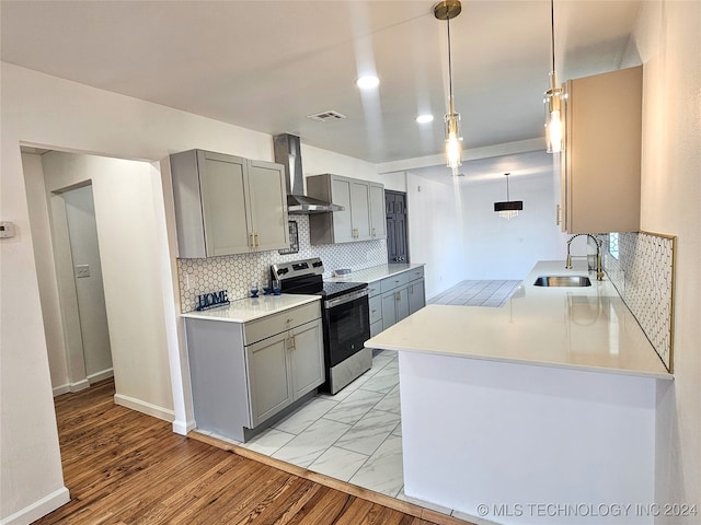 kitchen featuring hanging light fixtures, sink, wall chimney exhaust hood, electric range, and light wood-type flooring