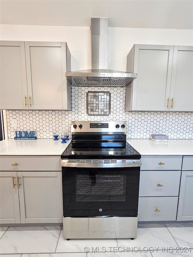 kitchen featuring tasteful backsplash, electric range, wall chimney exhaust hood, and gray cabinetry