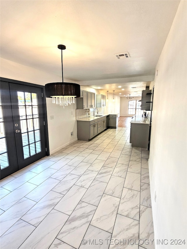 2532 N Martin Luther King Jr Blvd, Tulsa, OK 74106 - kitchen featuring light marble finish floors, gray cabinets, light countertops, a sink, and a chandelier