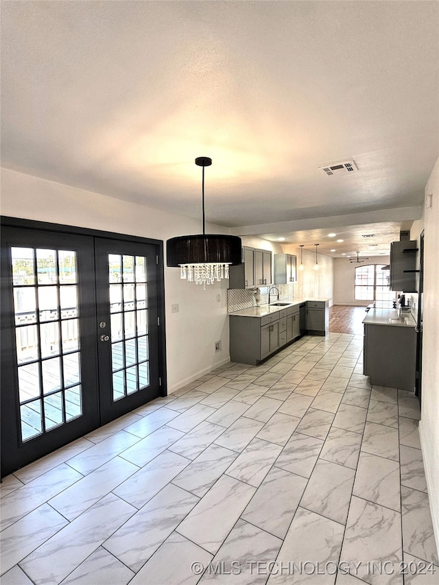 2532 N Martin Luther King Jr Blvd, Tulsa, OK 74106 - kitchen featuring light marble finish floors, light countertops, a sink, a chandelier, and french doors