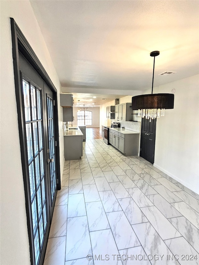 kitchen with stainless steel electric stove, a notable chandelier, and a wealth of natural light