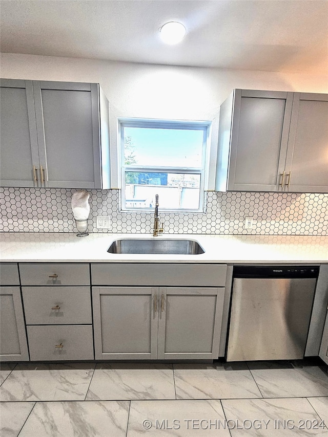 kitchen with gray cabinetry, sink, decorative backsplash, and stainless steel dishwasher