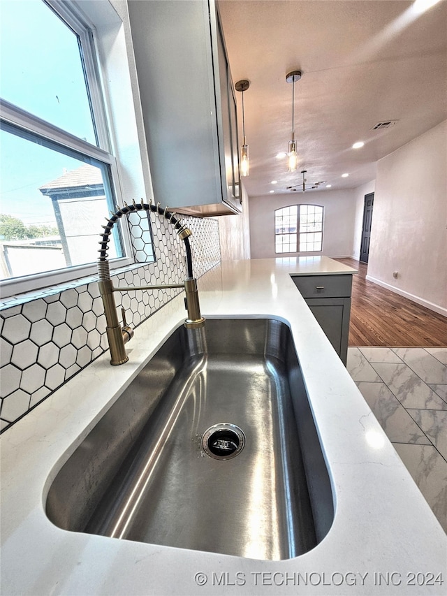 room details with hardwood / wood-style floors, decorative backsplash, decorative light fixtures, and sink