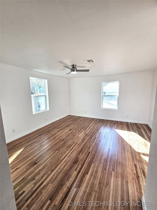 empty room featuring ceiling fan, dark hardwood / wood-style flooring, and a wealth of natural light