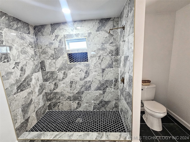 bathroom with tile patterned flooring, tiled shower, and toilet