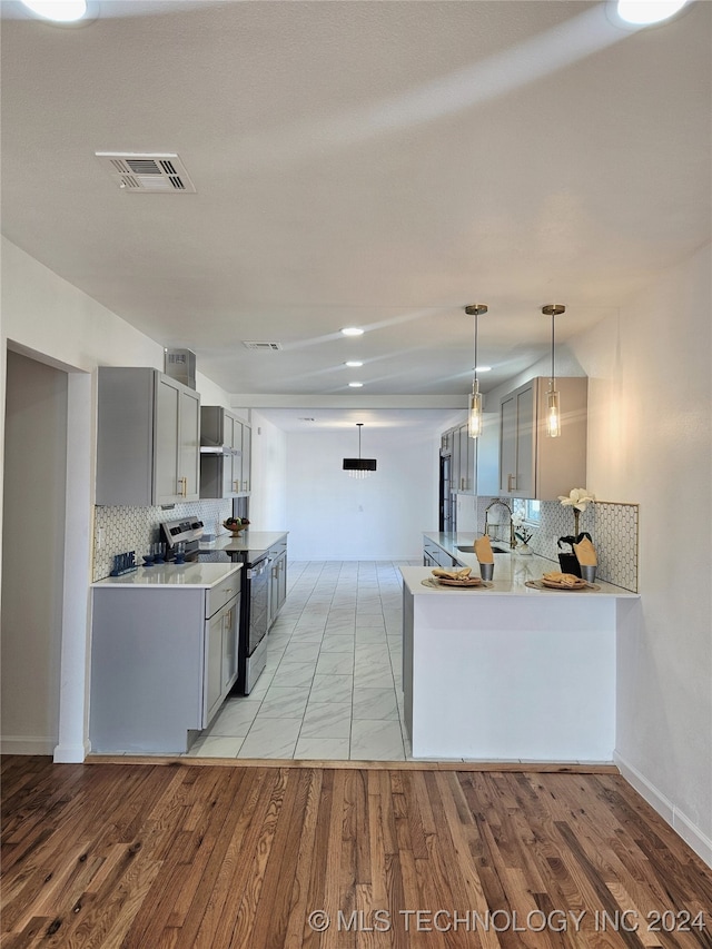 kitchen with pendant lighting, kitchen peninsula, gray cabinetry, light hardwood / wood-style flooring, and stainless steel electric stove