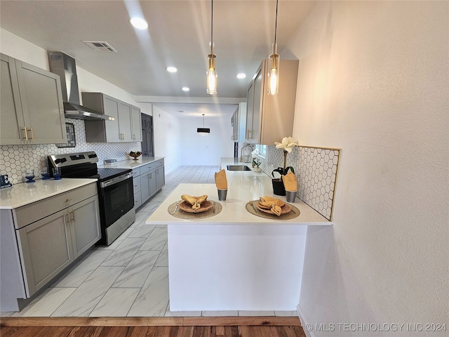 kitchen featuring stainless steel electric stove, sink, wall chimney range hood, decorative light fixtures, and backsplash